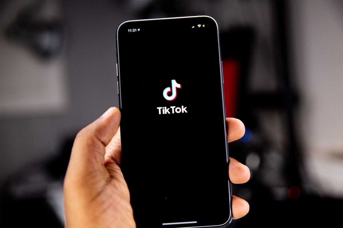 A hand holding a phone showing the TikTok logo