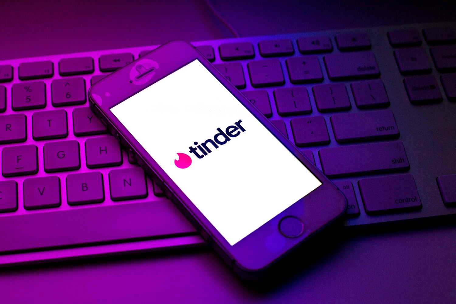 In this photo illustration a Tinder logo seen displayed on a smartphone on top of a computer keyboard.