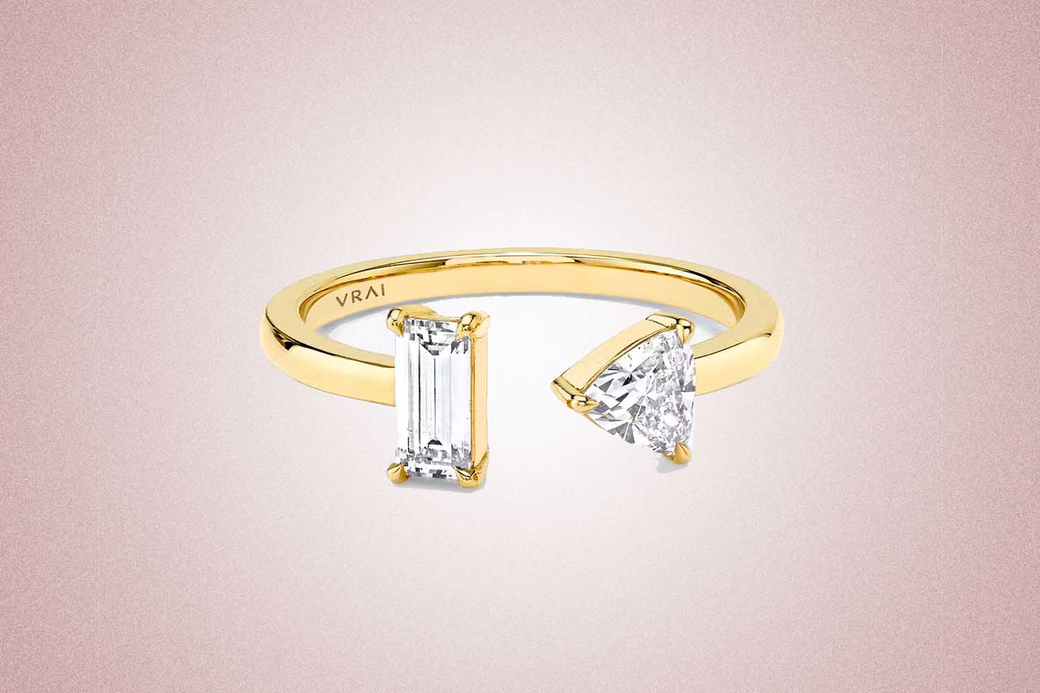 A gold ring with two diamonds, a perfect valentine's day gift, on a pink background.