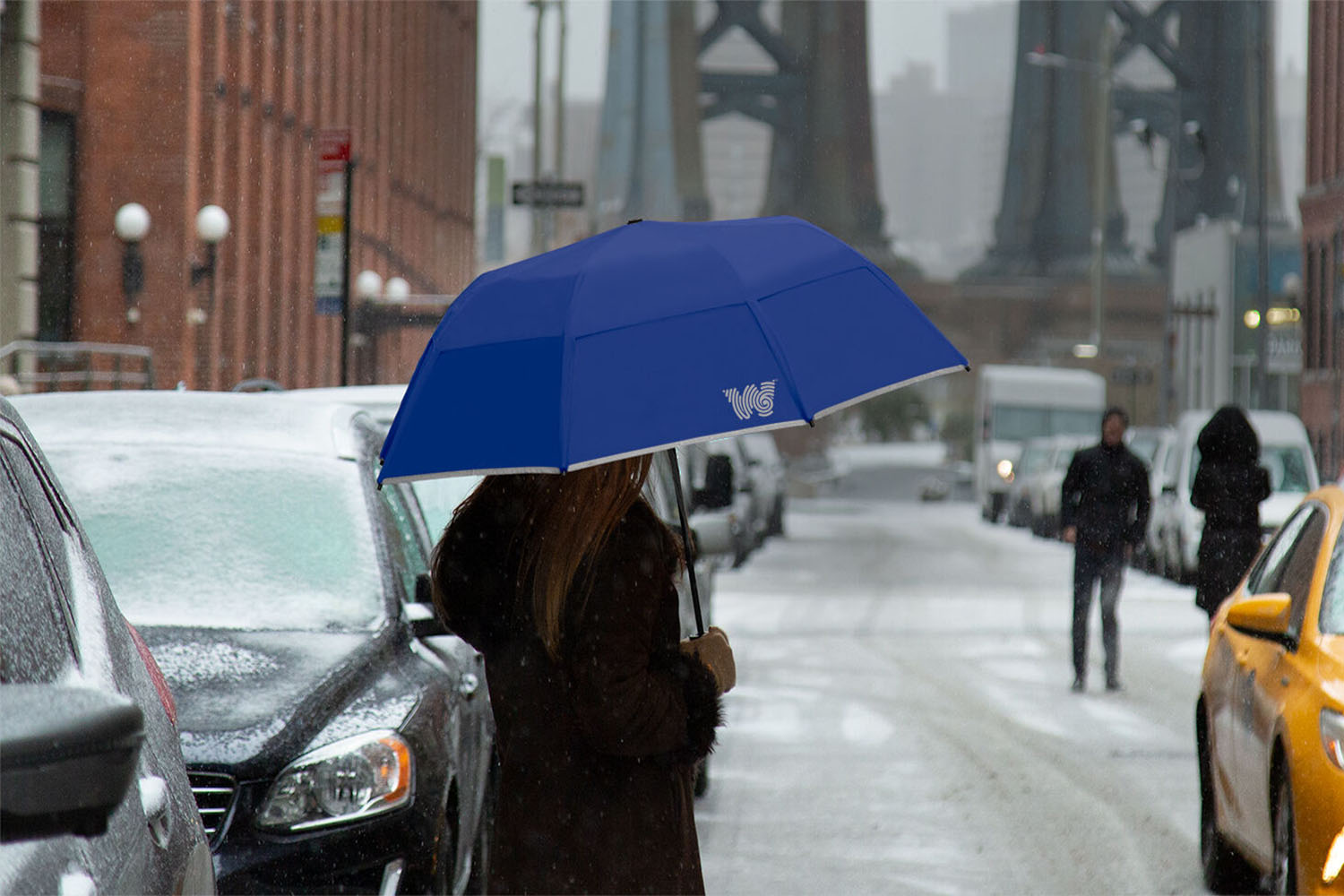 a woman carrying a cobalt blue umbrella in a snowy urban scape