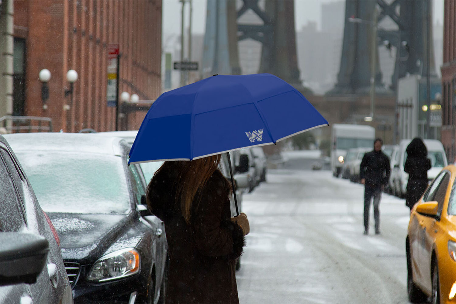 a woman carrying a cobalt blue umbrella in a snowy urban scape 
