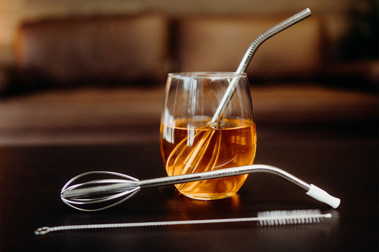 a glass of Whiskey with the whiskee straw inside