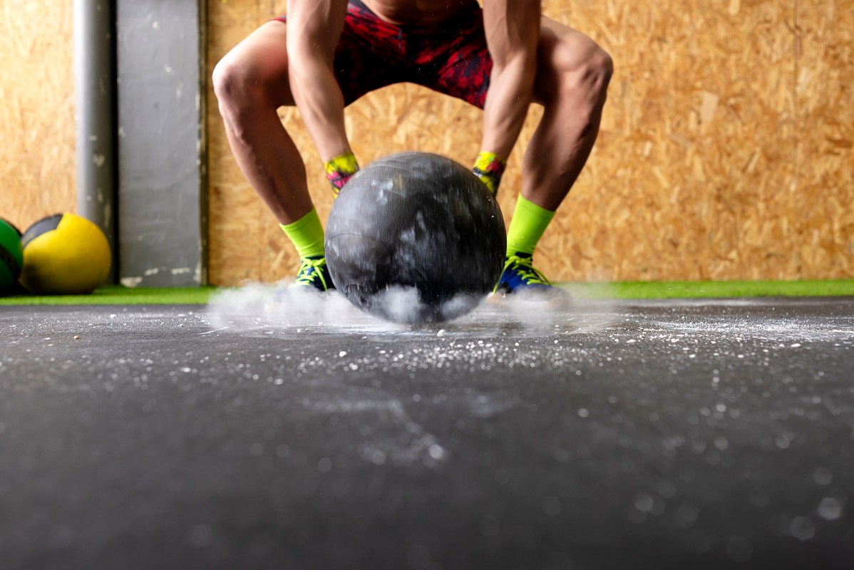 A man throwing a medicine ball at the ground.