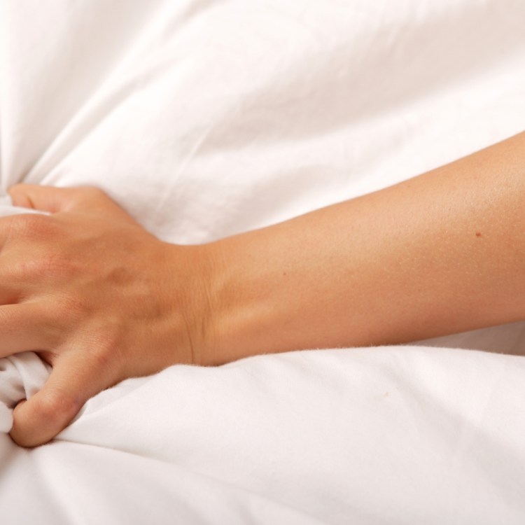 Close-up photo of a woman's hand clutching a sheet