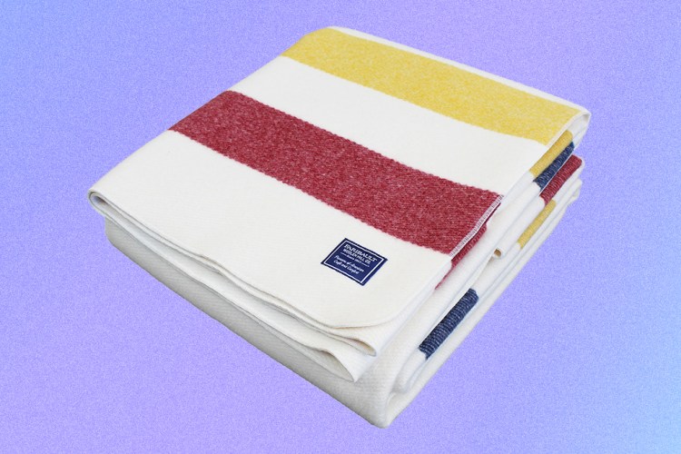 The Frontier Wool Blanket from Faribault Woolen Mill Co. in bone white with red, blue and yellow stripes. The American-made blanket is on sale in February 2022.