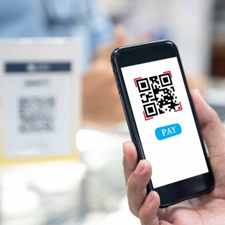 A person holding up a smartphone and scanning a QR code. In January 2022, the FBI warned about scammers manipulating QR codes.