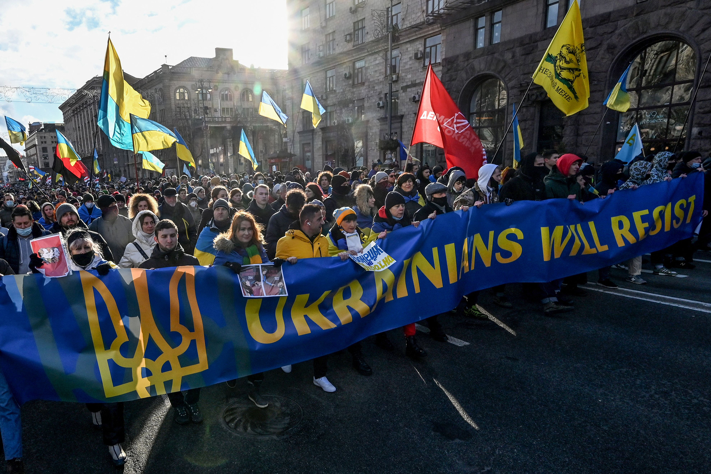 Demonstrators march behind a banner in the colors of the national flag during a rally in Kyiv in February