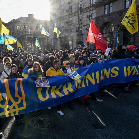 Demonstrators march behind a banner in the colors of the national flag during a rally in Kyiv in February
