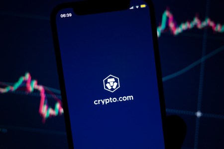 A phone depicting Crypto.com against a background of stocks.
