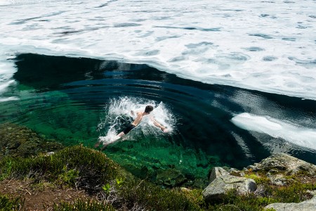 A man jumping into freezing cold water. Healthy stress, like extreme temperatures, could help you add years to your life.