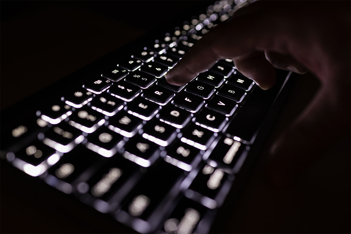 A man typing in the dark.