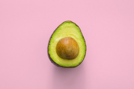 An avocado against a pink background.