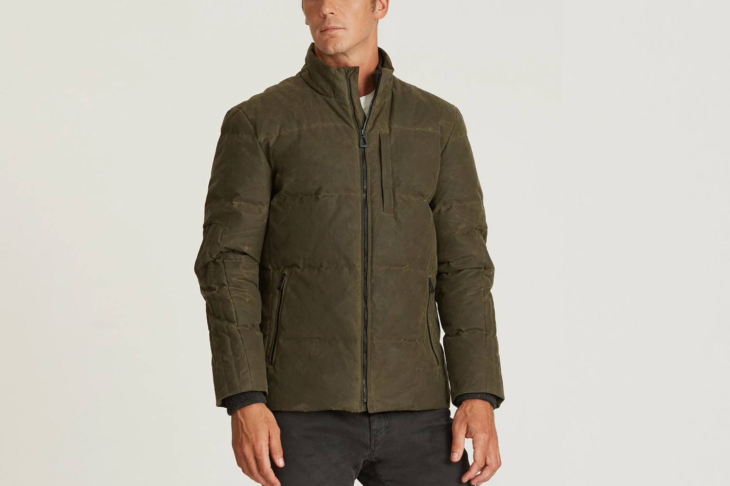 Aether Camber Jacket is dark green on a beige background