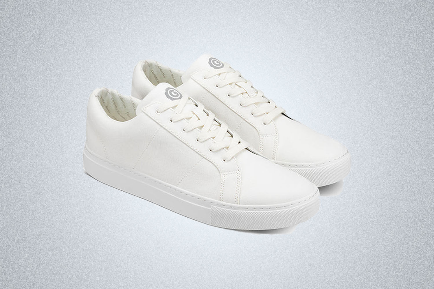 a pair of white sneakers on a grey background 