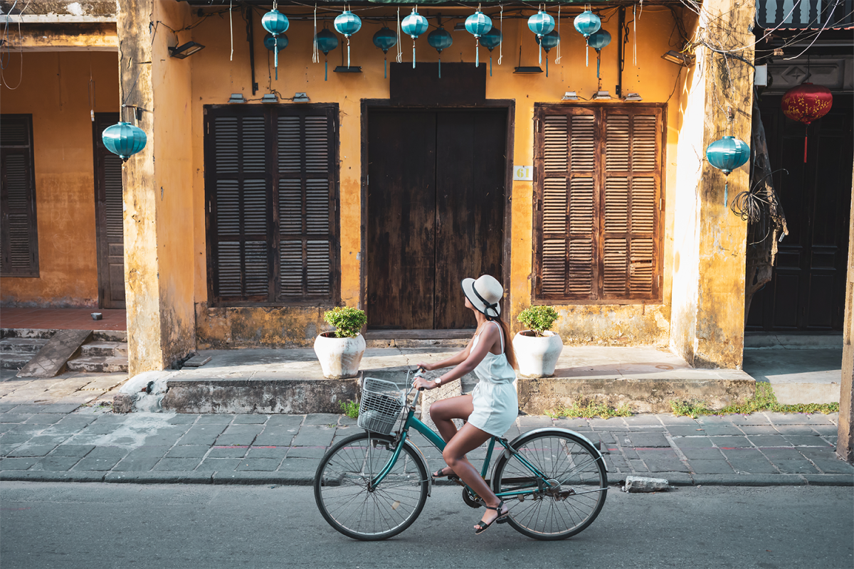A woman riding a bicycle down a street. We look at the latest vacation trend: heritage travel.