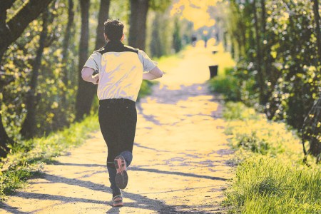 A man running along a wooded trail in springtime.