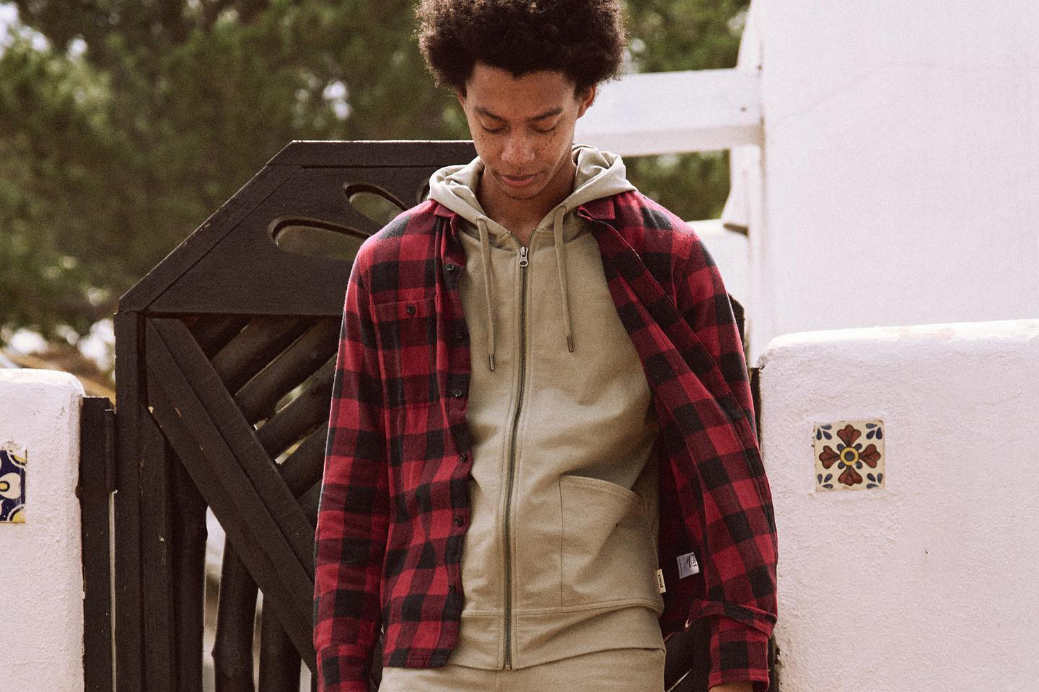 Pact apparel on a man wearing a red and black flannel top with a tan shirt underneath