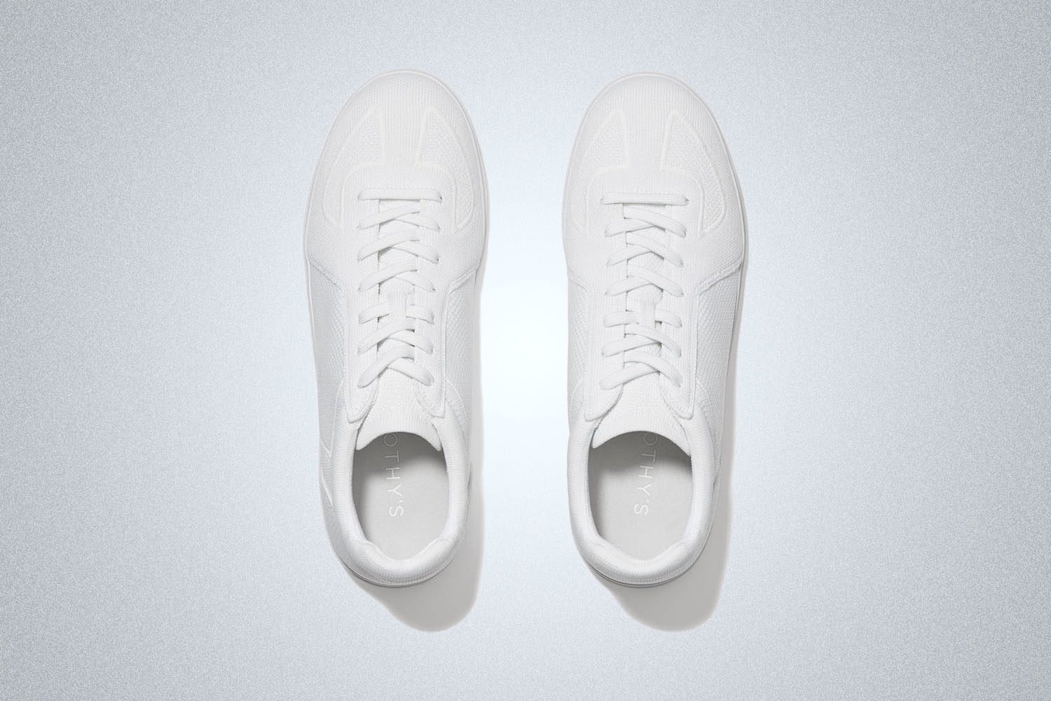 a pair of white sneakers on a grey background