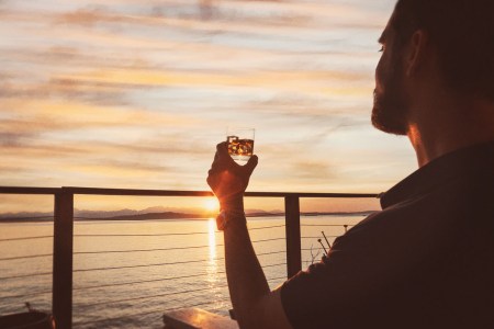 A man sitting near the water drinking whiskey on the rocks and looking at the sky. The concept of "smooth" as an adjective in whisky is contentious.