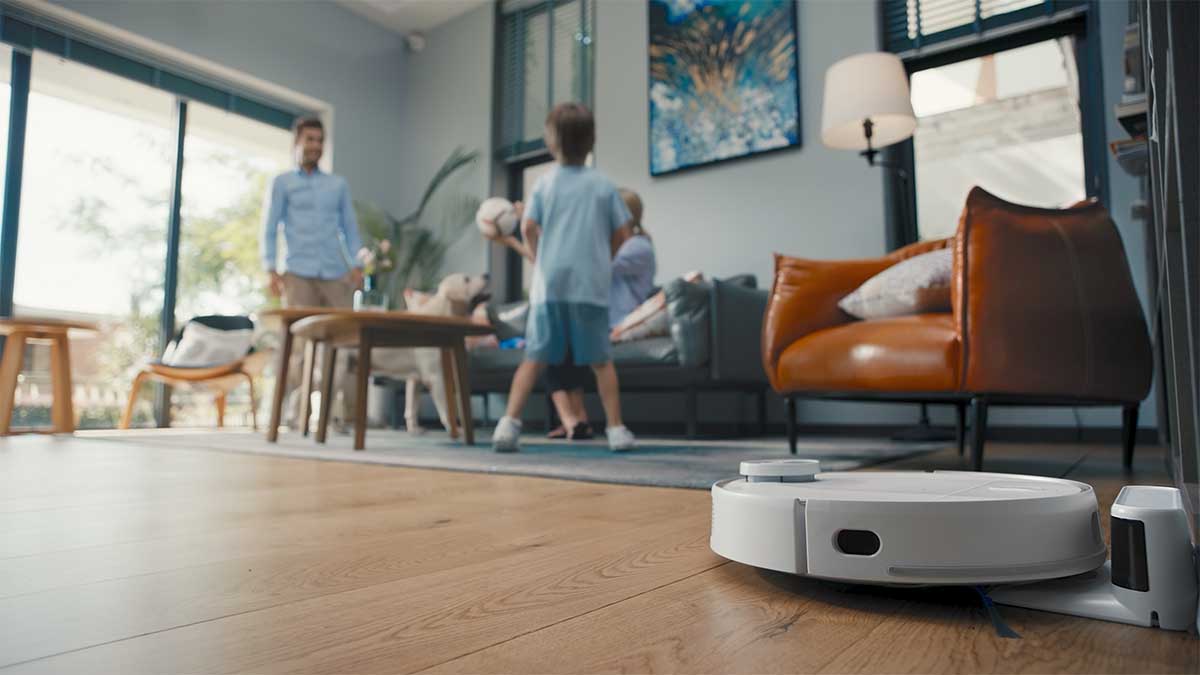 eufy RoboVac in action on a living room floor while a father and son play nearby. The RoboVacs are currently on sale at Amazon.