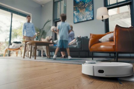 eufy RoboVac in action on a living room floor while a father and son play nearby. The RoboVacs are currently on sale at Amazon.