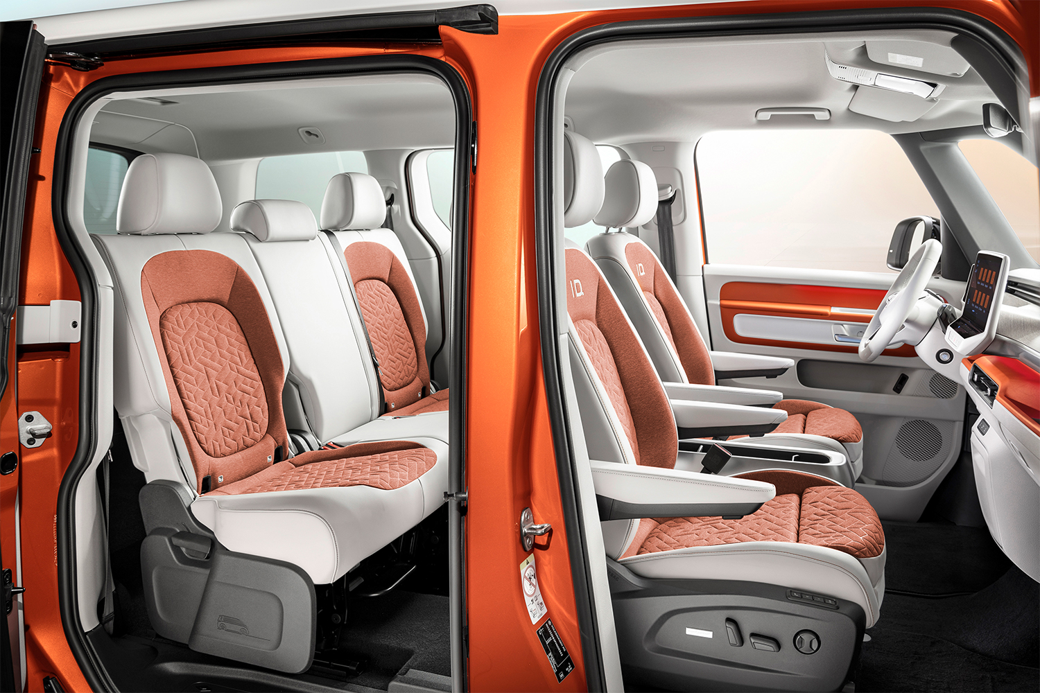 The interior of the new Volkswagen ID. Buzz, an electric passenger van based on the VW Microbus, showing white and orange seats in two rows