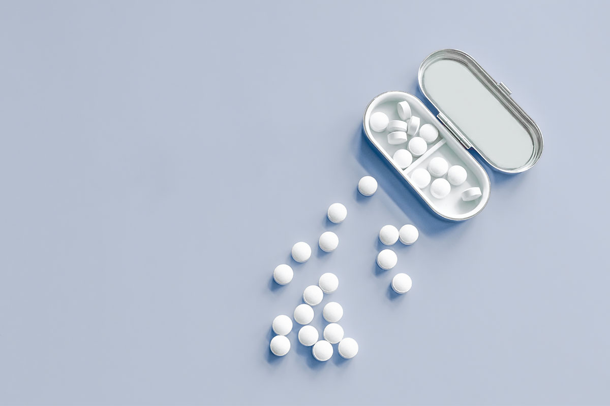 An array of melatonin caplets against a blue background.