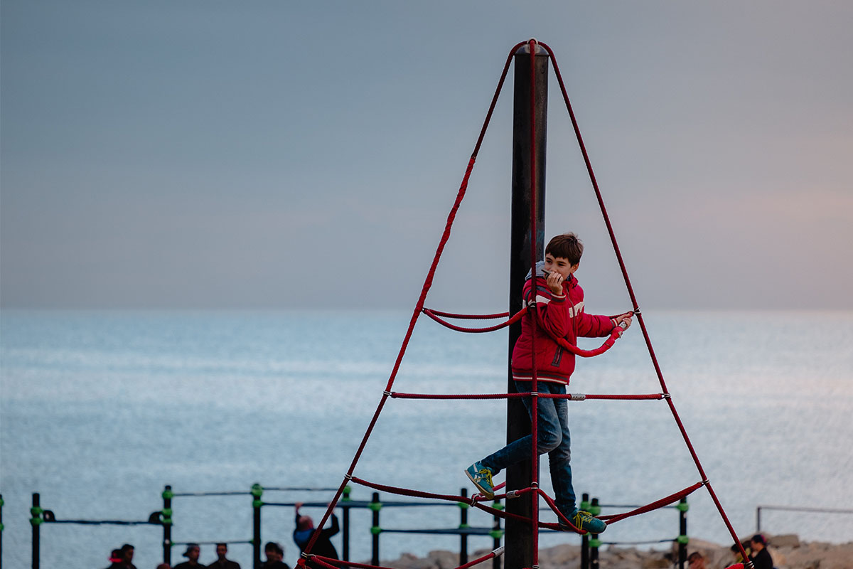 A boy on a playground near the ocean. This is an example of "risky play," but is it right for your kid? Parents are fighting about it online.