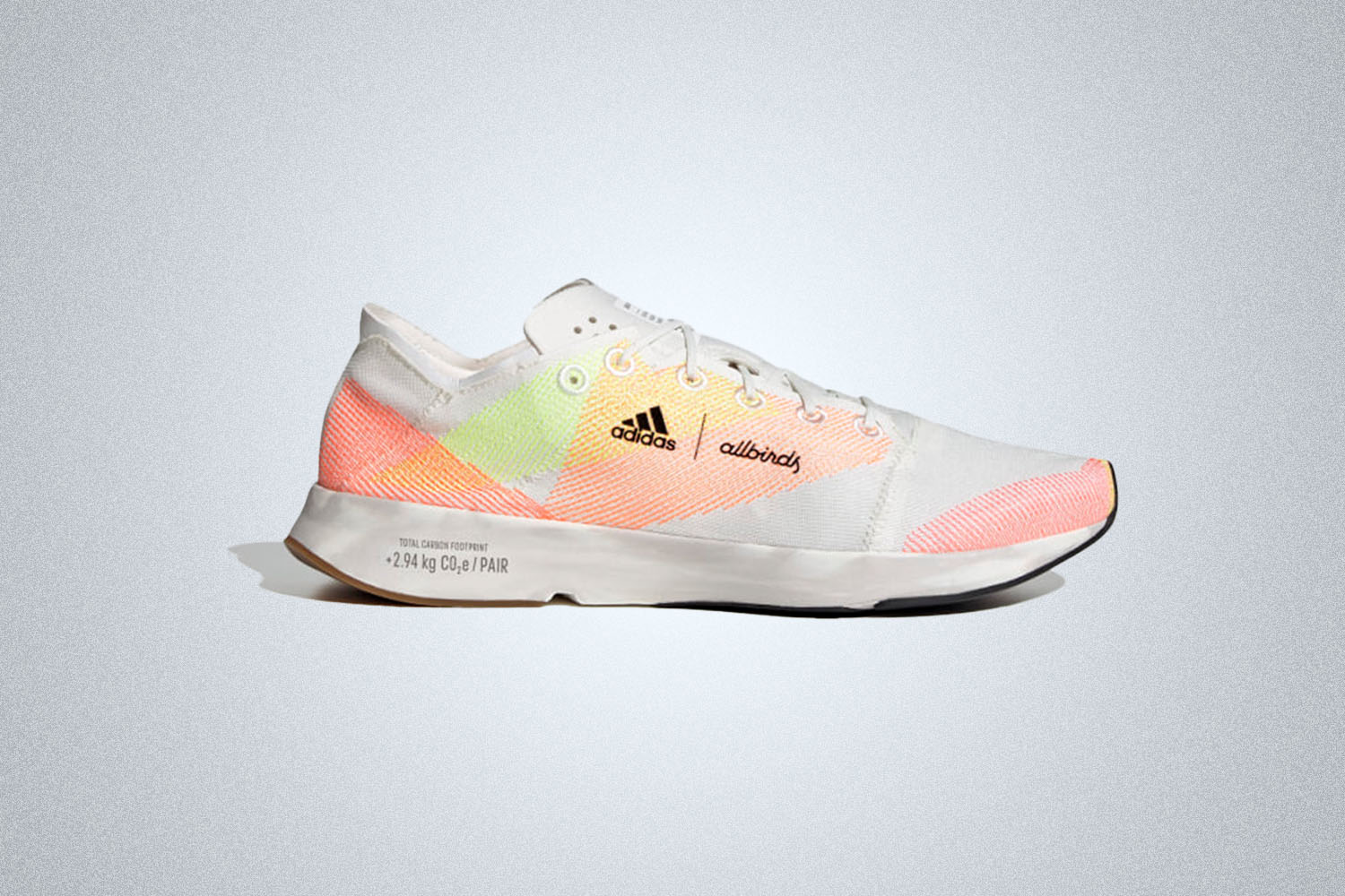 a white Adidas sneaker with pink, orange and yellow pattering on a grey background