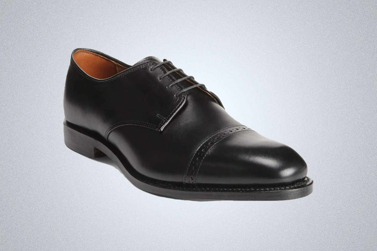 A black pair of Allen Edmonds Oxford shoes on a grey background