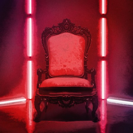An empty, throne-like chair is illuminated by vibrant red lights.