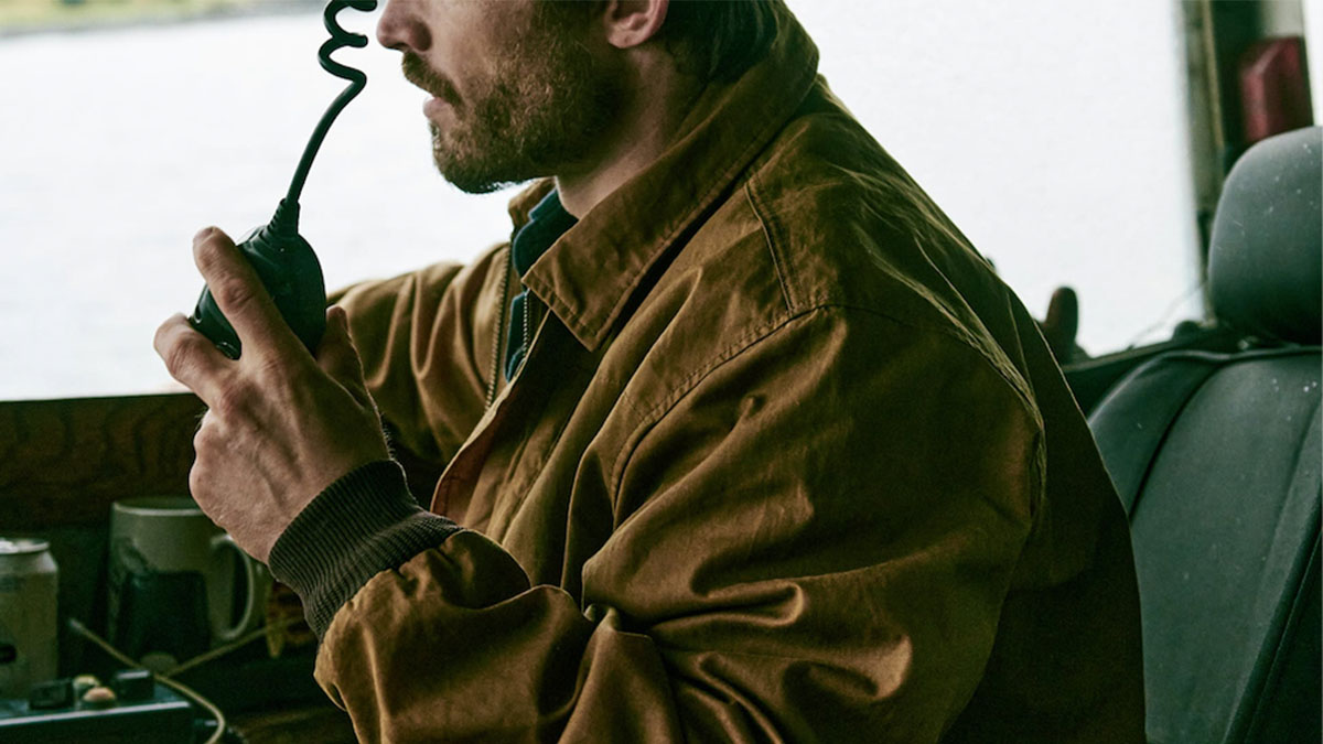 A model wearing a Filson Aberdeen Jacket driving a truck.