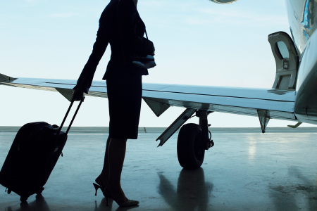 A flight attendant rolling a suitcase next to an airplane wing. According to a new report from The Boston Globe, many flight attendants are sharing "crash pads" with multiple shared bunk beds.