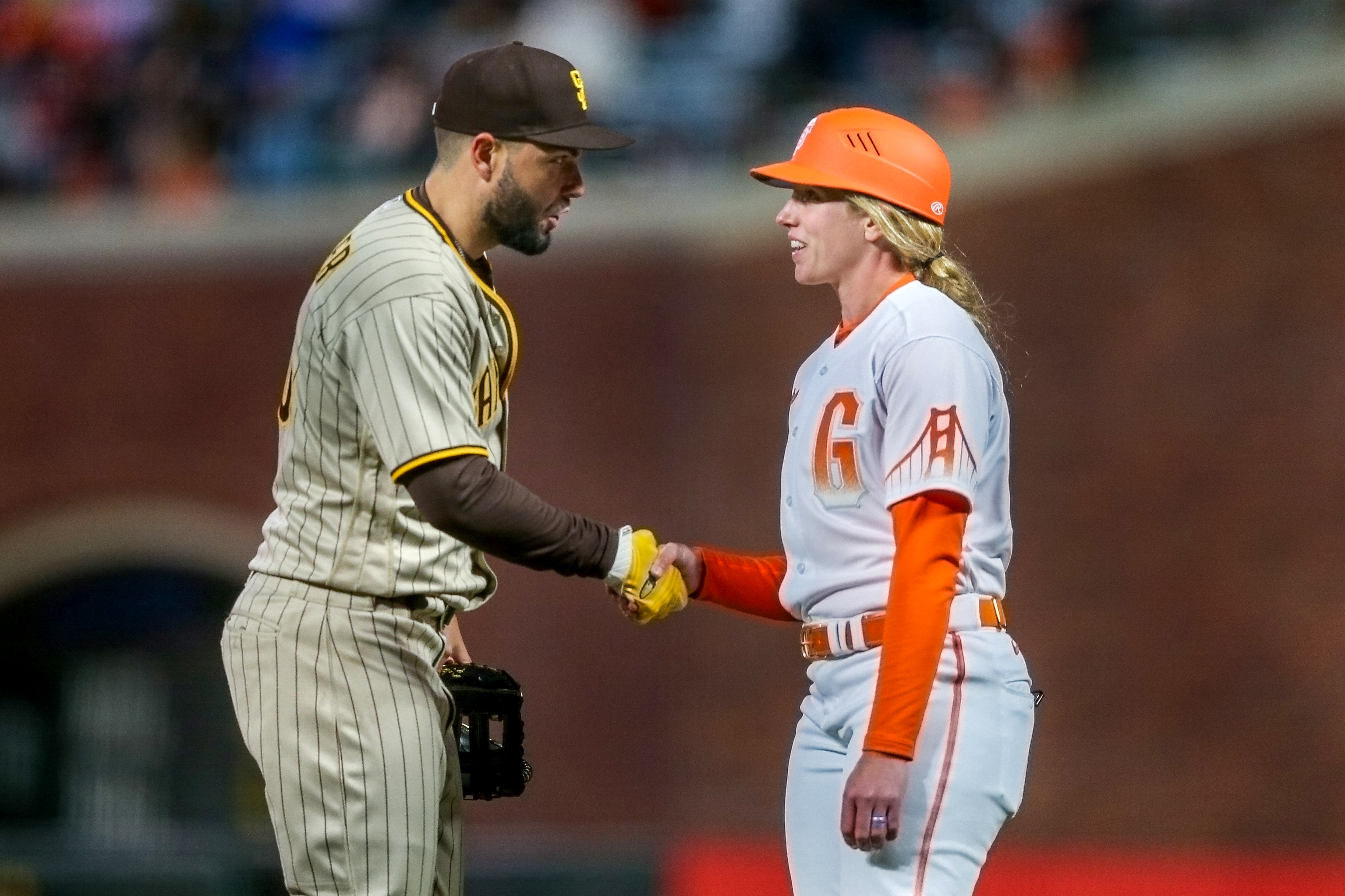 San Diego Padres' Eric Hosmer greets San Francisco Giants first base coach Alyssa Nakken in the fourth inning on April 12. Nakken made history as the first woman to coach on the field in a regular season game.