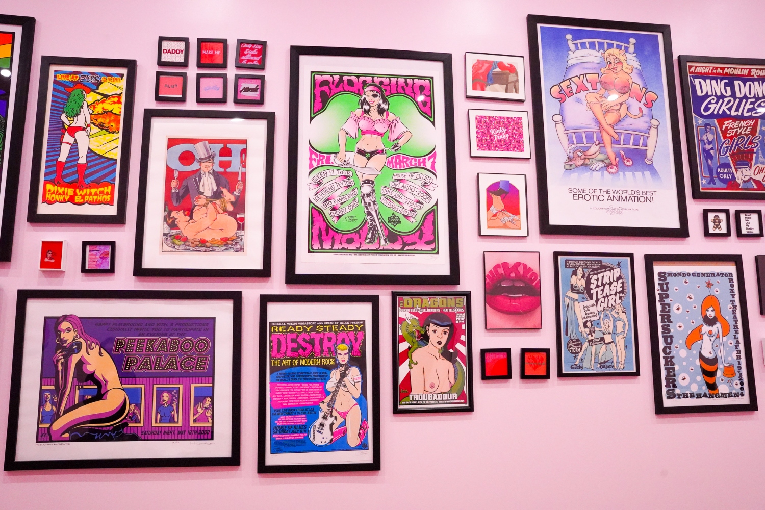 A gallery of vintage erotic posters lines a pink wall at Kinky's Dessert Bar