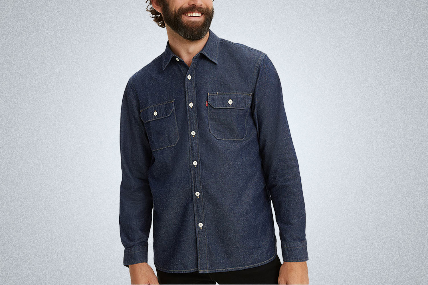 A model in a dark blue Levi's denim shirt on a grey background