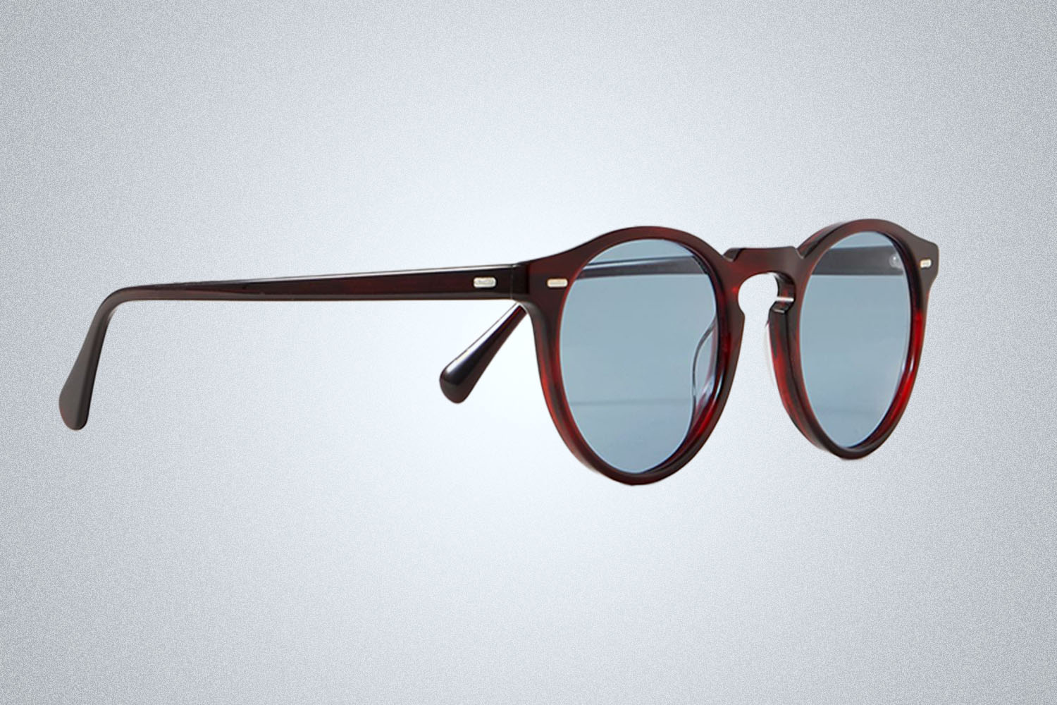 a pair of designer sunglasses from Oliver Peoples on a grey background