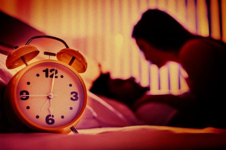 A shadowy image of a couple having sex in the background, a clock in the foreground.