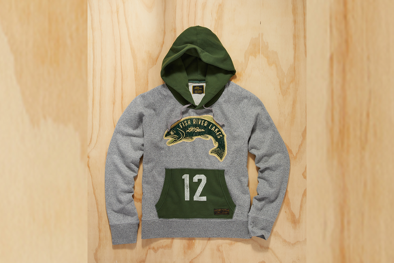 a grey and green hoodie with fish graphic on a wood background