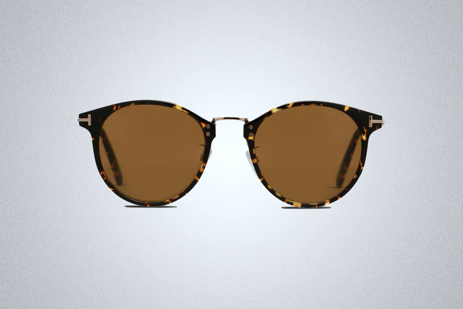 a pair of circular, tortoise-shell Tom Ford sunglasses on a grey background