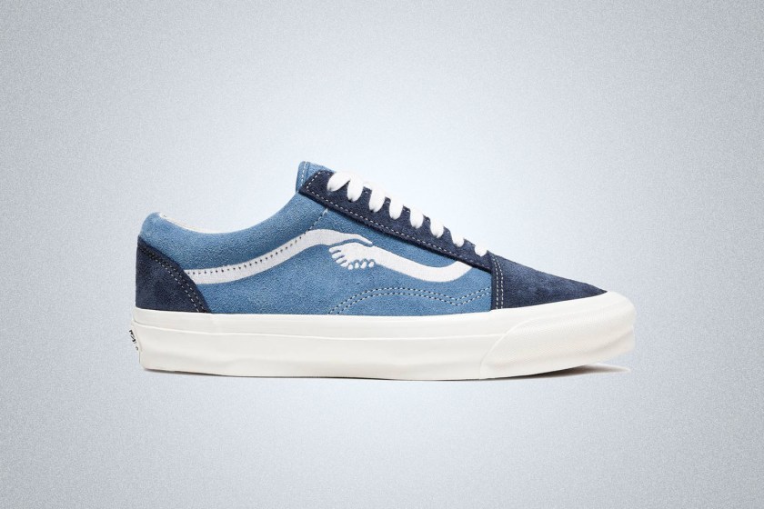 a blue Vans x Notre sneaker with hand-holding graphic on a grey background 