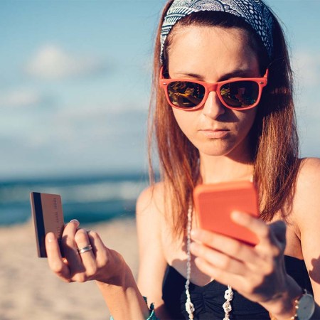 Young woman on the beach phoning the bank for credit card support. Fraud, both in calls and online, is more likely to affect younger people.