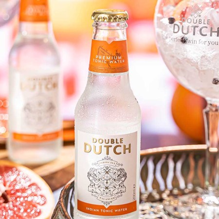 Two bottles of Double Dutch Indian Tonic Water on a table near a glass