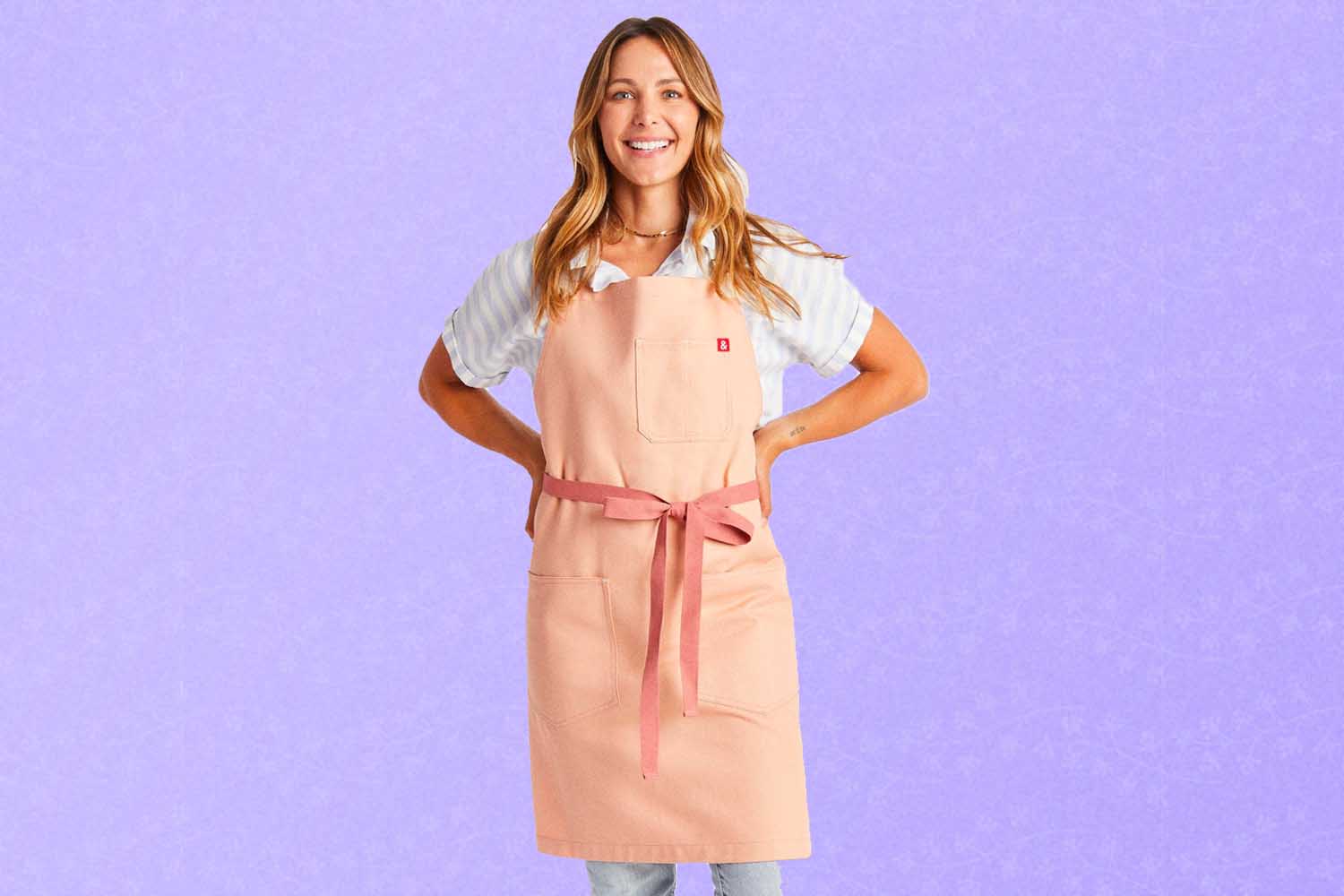 A pink Hedley & Bennett apron, a perfect Mother's Day gift for 2022, on a purple background.