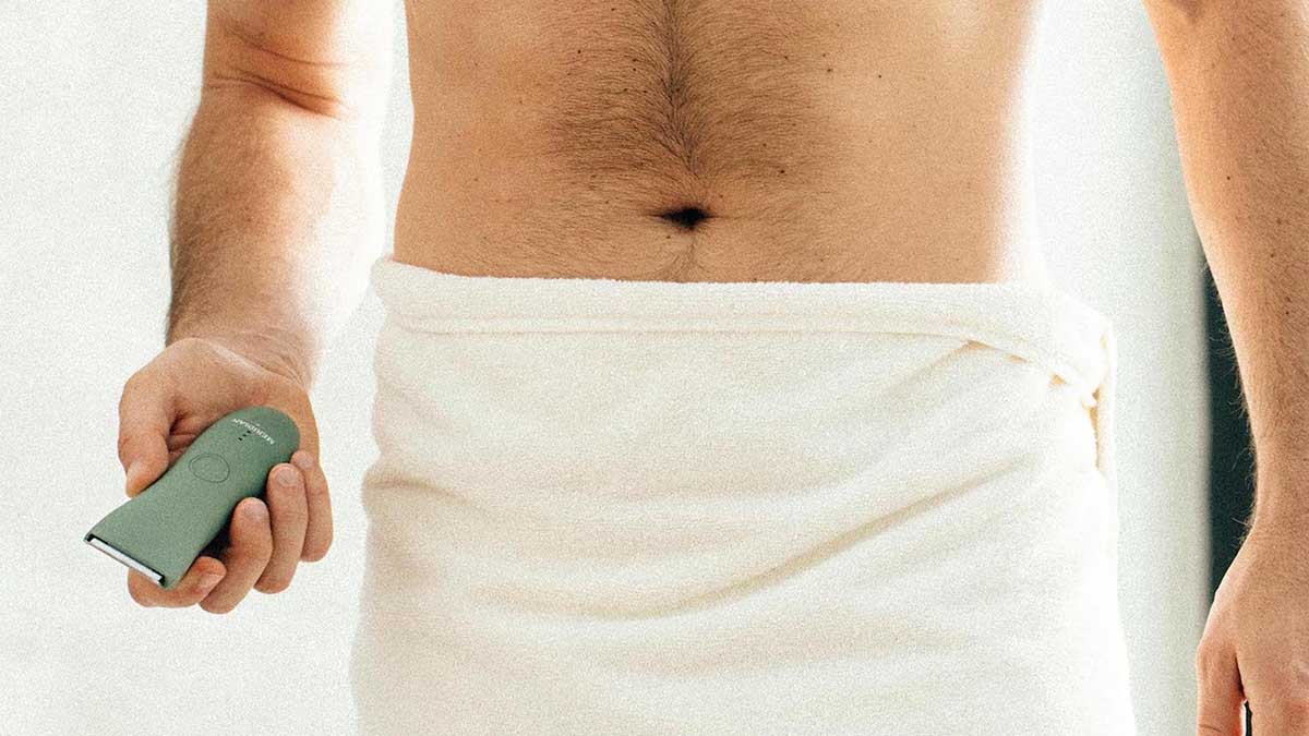 A man in a towel holding the Trimmer by Meridian, an electric shaver for "down there"