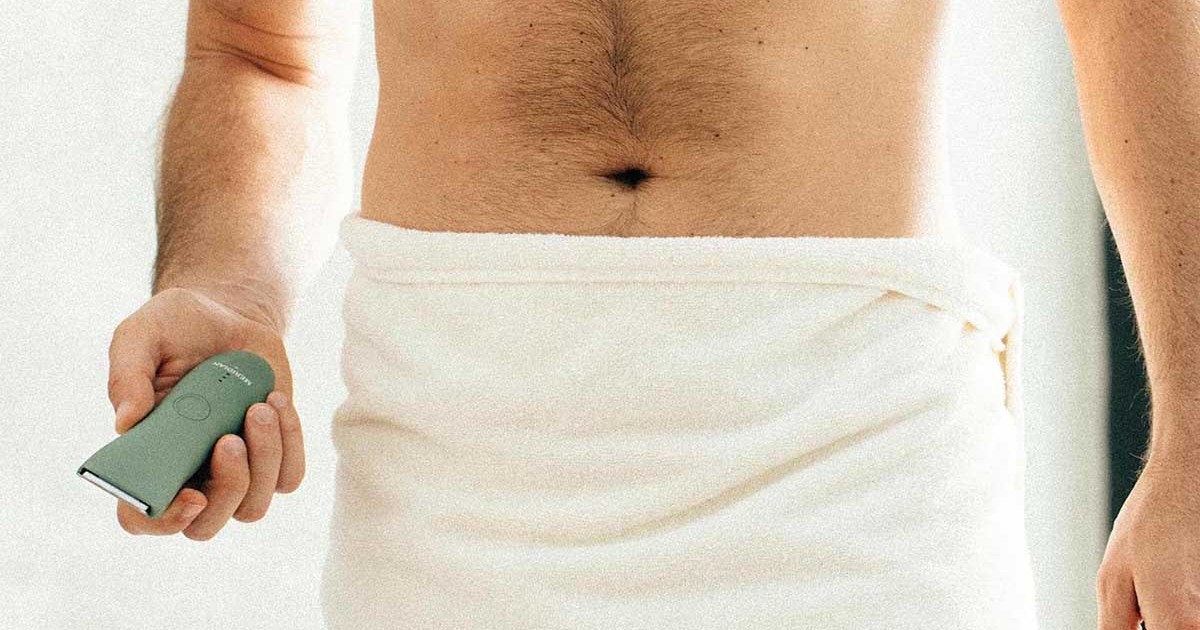 A man in a towel holding the Trimmer by Meridian, an electric shaver for "down there"