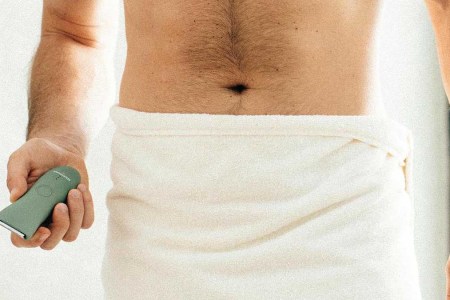 A man in a towel holding the Trimmer by Meridian, an electric shaver for "down there"
