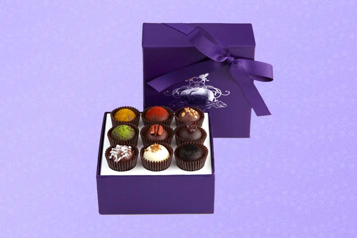 A box of chocolate truffles, a perfect Mother's Day gift for 2022, on a purple background.