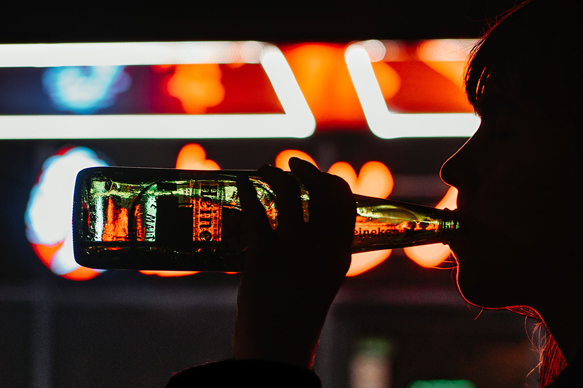 A woman drinking a Heineken in a dark room Are you a grey area drinker? The term has come up more as people consume more alcohol during the pandemic..