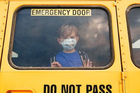A child wearing a mask on a school bus.